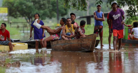Des habitants utilisent une barque pour traverser un zone inondée dans le quartier Joaia do Atlantico, à Ilheus, dans le sud de l'Etat brésilien de Bahia.