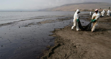 Des équipes de nettoyage ramassent le pétrole d'une plage près de la station balnéaire d'Ancon, à Lima, au Pérou, le 20 janvier 2022.