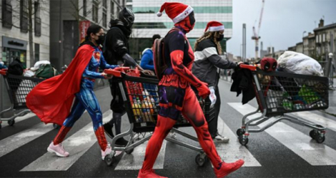 Des membres d'un collectif déguisés en super-héros, dont sa fondatrice Océane Gaixet (C), poussent des chariots remplis de vivres et de vêtements pour les sans-abris, le 8 janvier 2022 à Bordeaux. afp.com - Philippe LOPEZ