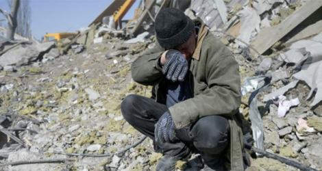 Un homme aide des soldats ukrainiens recherchant des corps dans les ruines d'une caserne bombardée par les forces russes à Mykolaïv, dans le sud de l'Ukraine, le 19 mars 2022.