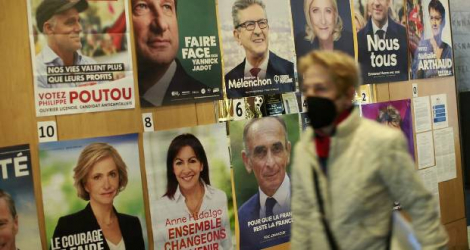 Une femme passe devant les affiches électorales des candidats à la présidentielle, près du lycée français à New York où des électeurs commençaient à voter, le 9 avril 2022 Kena Betancur AFP