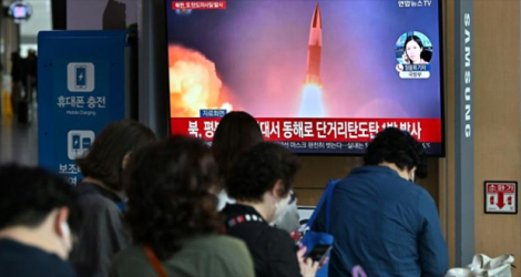 Des voyageurs devant un écran de télévision montrant des images d'archives d'un test de missile nord-coréen, dans une gare de Séoul, le 25 septembre 2022.