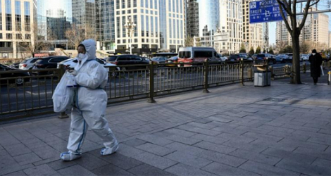Une femme portant une tenue de protection sanitaire, dans une rue de Pékin le 26 décembre 2022.
