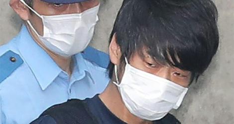 Tetsuya Yamagami (d), soupçonné du meurtre de l'ancien Premier ministre Shinzo Abe, escorté par un policier à la sortie du poste de police de Nara, le 10 juillet 2022 dans l'ouest du Japon.