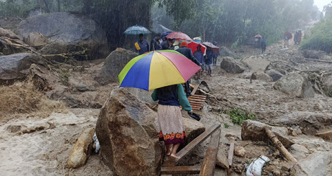 Des habitants traversent un pont de fortune qui enjambe des eaux de crue, le 14 mars 2023 à Blantyre (Malawi).
