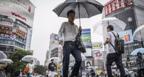 Des piétons traversent le carrefour de Shibuya s'abritant de la pluie sous leurs parapluies, le 2 juin 2023 à Tokyo.