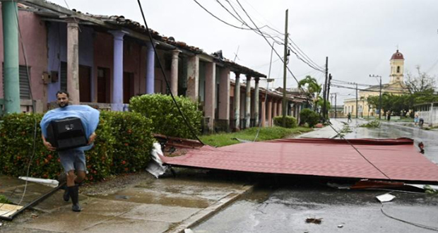 Un homme porte une télévision pour la protéger des rafales de vent au passage de l'ouragan Ian qui a emporté des toitures à Consolacion del Sur, dans l'ouest de Cuba, le 27 septembre 2022.