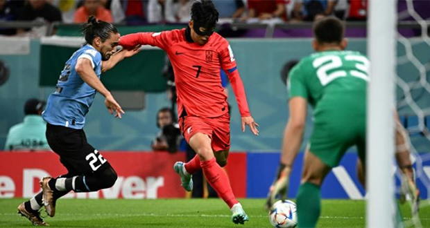 La star sud-coréenne Son Heung-min, marqué par l'Uruguayen Martin Caceres, lors du Mondial au Qatar, 24 novembre 2022 au stade d'Al-Rayyan.