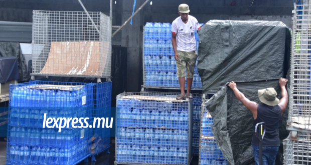 Des employés tentent de recouvrir des stocks de bouteilles d’eau qui devaient être distribuées et vendues, avant le communiqué.