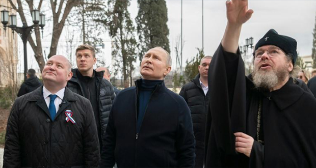 Photo prise et transmise par les services de la présidence russe à Sébastopol le 18 mars 2023 montrant Vladimir Poutine (C) lors d'une visite surprise en Crimée pour le 9ᵉ anniversaire de l'annexion de cette péninsule ukrainienne par la Russie.